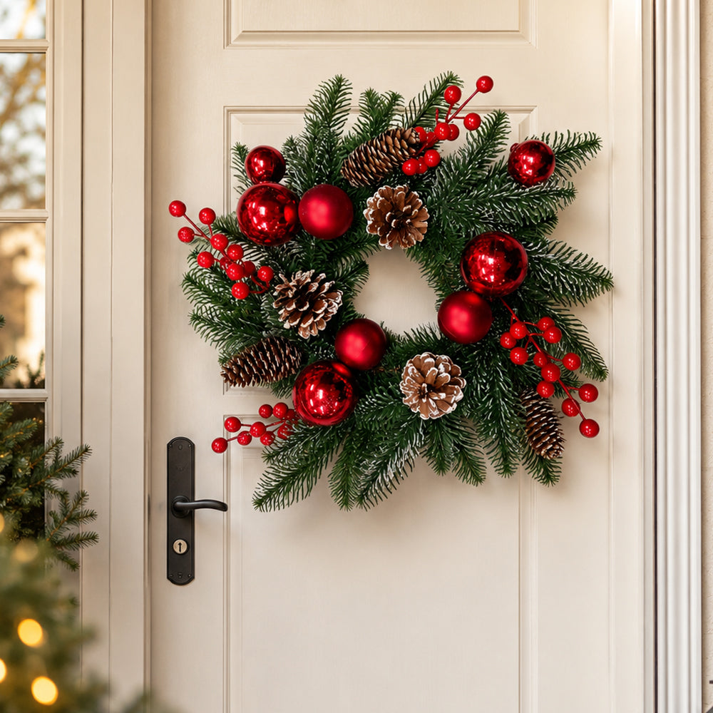 Kerstkrans met rode kerstballen, bessen en dennenappels