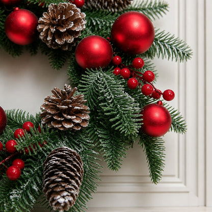 Kerstkrans met rode kerstballen, bessen en dennenappels