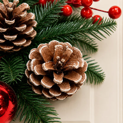 Kerstkrans met rode kerstballen, bessen en dennenappels