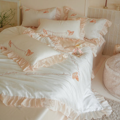 Luxe satijnen beddengoedset met chiffonachtige ruches, geborduurde vlindermotieven en elegante handgeschreven applicatie