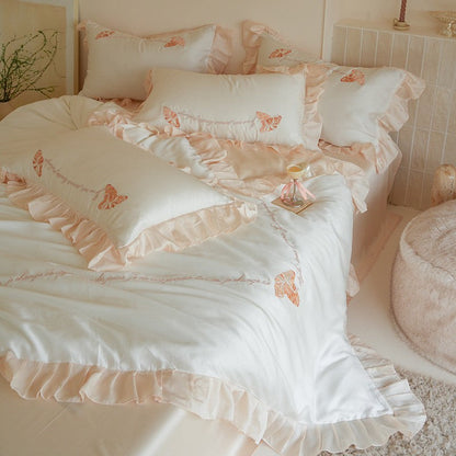 Luxe satijnen beddengoedset met chiffonachtige ruches, geborduurde vlindermotieven en elegante handgeschreven applicatie