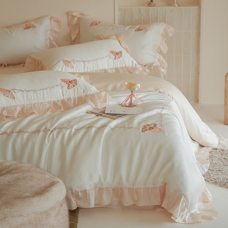 Luxe satijnen beddengoedset met chiffonachtige ruches, geborduurde vlindermotieven en elegante handgeschreven applicatie