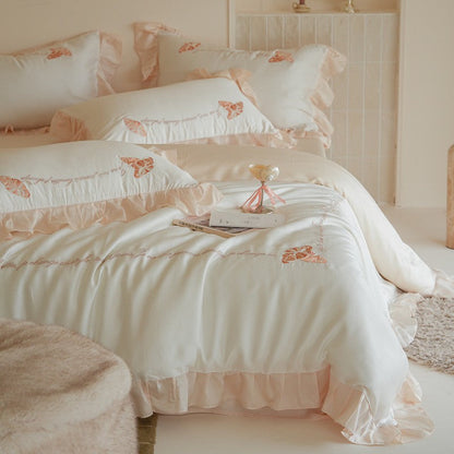 Luxe satijnen beddengoedset met chiffonachtige ruches, geborduurde vlindermotieven en elegante handgeschreven applicatie