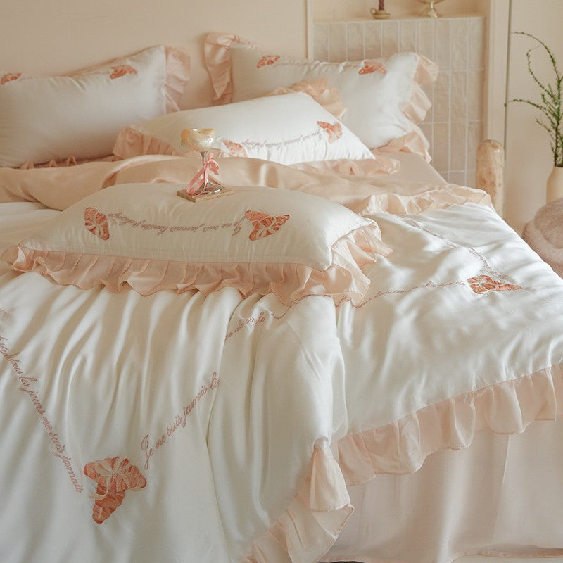 Luxe satijnen beddengoedset met chiffonachtige ruches, geborduurde vlindermotieven en elegante handgeschreven applicatie