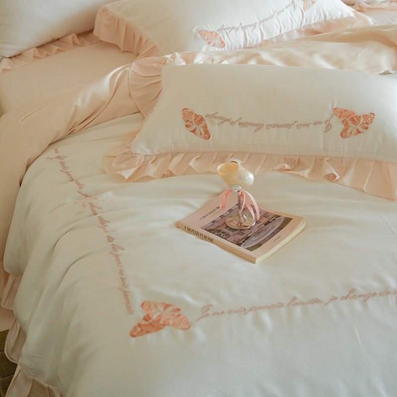 Luxe satijnen beddengoedset met chiffonachtige ruches, geborduurde vlindermotieven en elegante handgeschreven applicatie