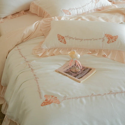 Luxe satijnen beddengoedset met chiffonachtige ruches, geborduurde vlindermotieven en elegante handgeschreven applicatie